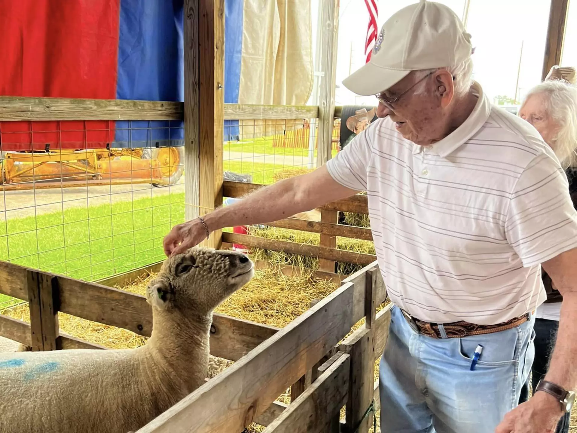 A StoryPoint Group resident is at a petting farm, petting a sheep on the head. 