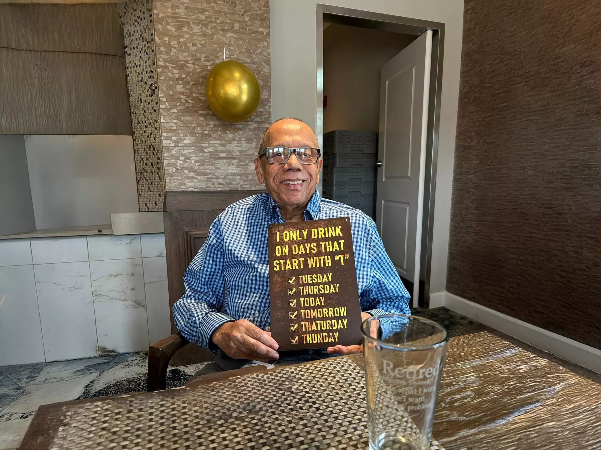A StoryPoint Group resident enjoying happy hour at the community, holding a sign that says 