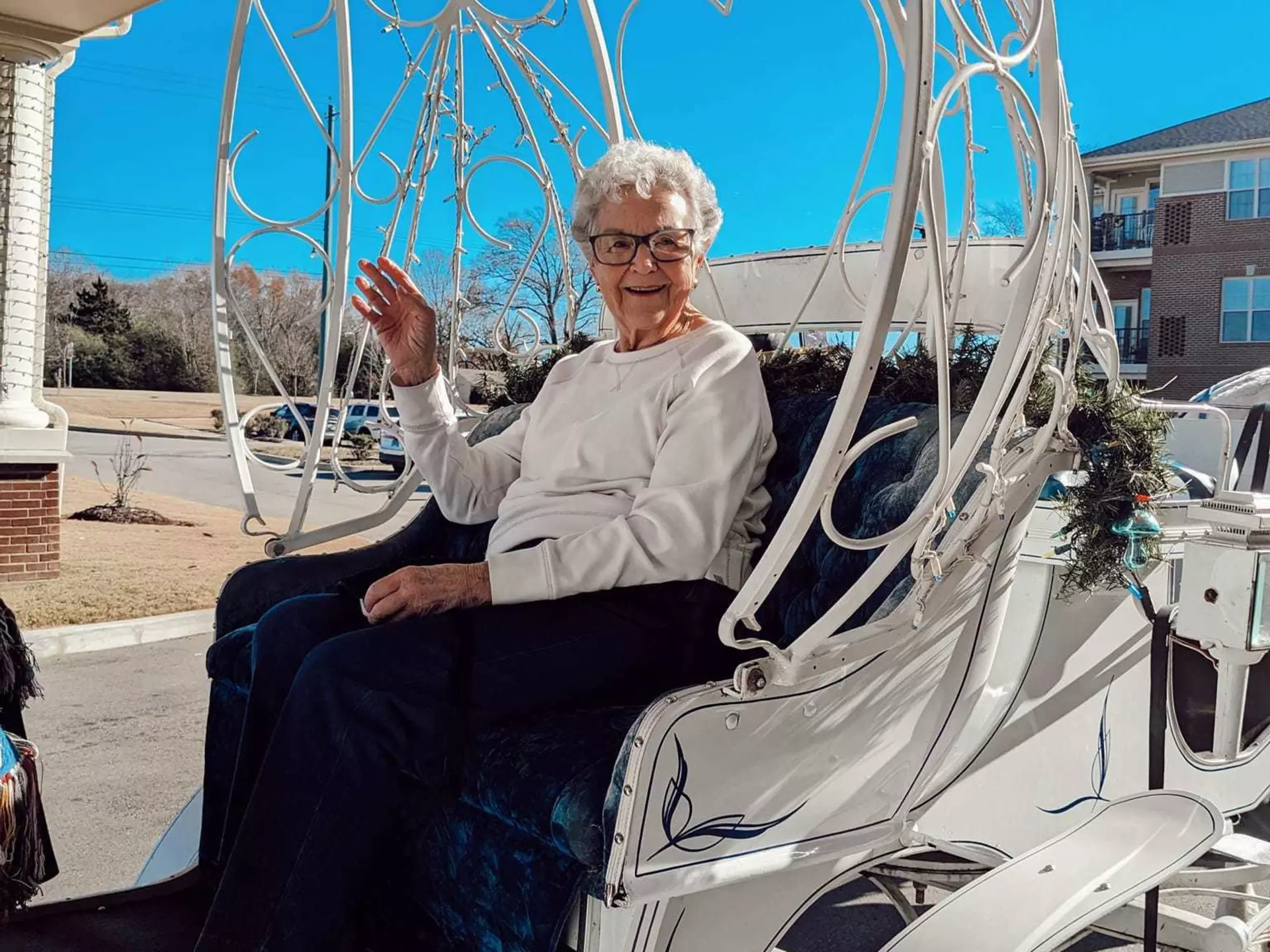 A StoryPoint Group resident is waving to the camera while riding in a horse-drawn carriage.